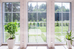 Bright Interior Of The Room In A Wooden House With A Large Window Overlooking The Summer Courtyard.