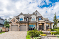 Beautiful exterior of newly built luxury home. Yard with green grass and walkway lead to front entra