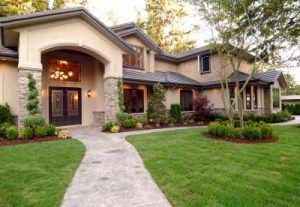 A Home Exterior With Green Grass and an Attractive Entryway Leading to Brown Front Doors