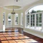 Large windows letting in a lot of light in an empty room with hardwood floors 